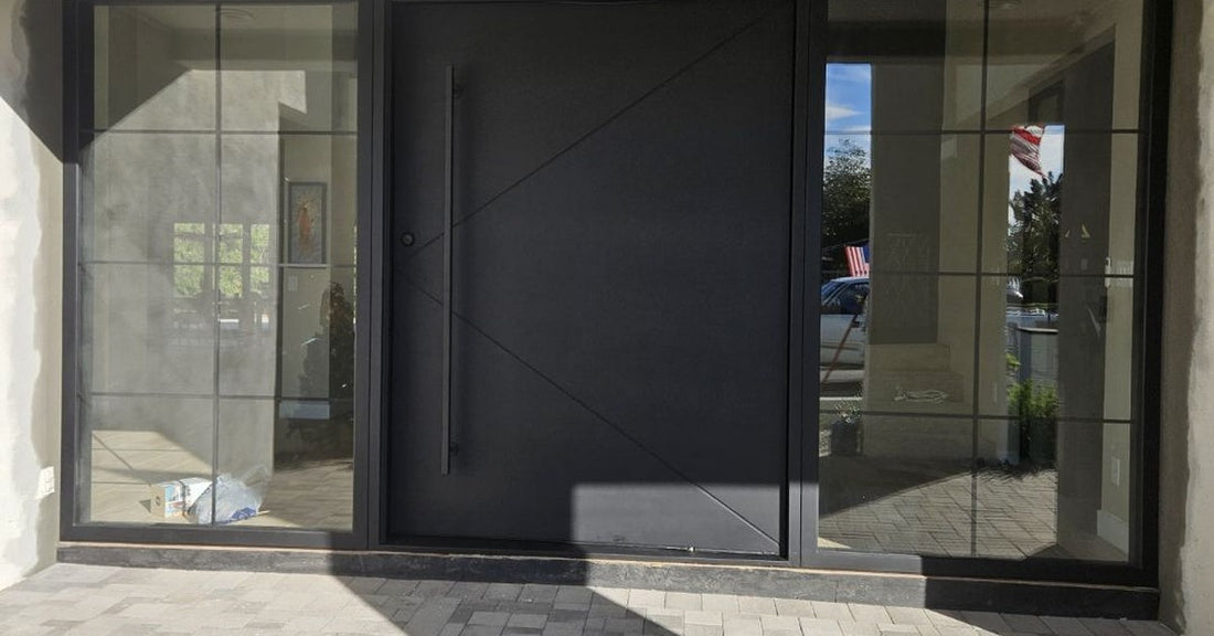 Large-format modern pivot door framed by floor-to-ceiling glass sidelights, creating a dramatic entrance with a sophisticated architectural aesthetic.