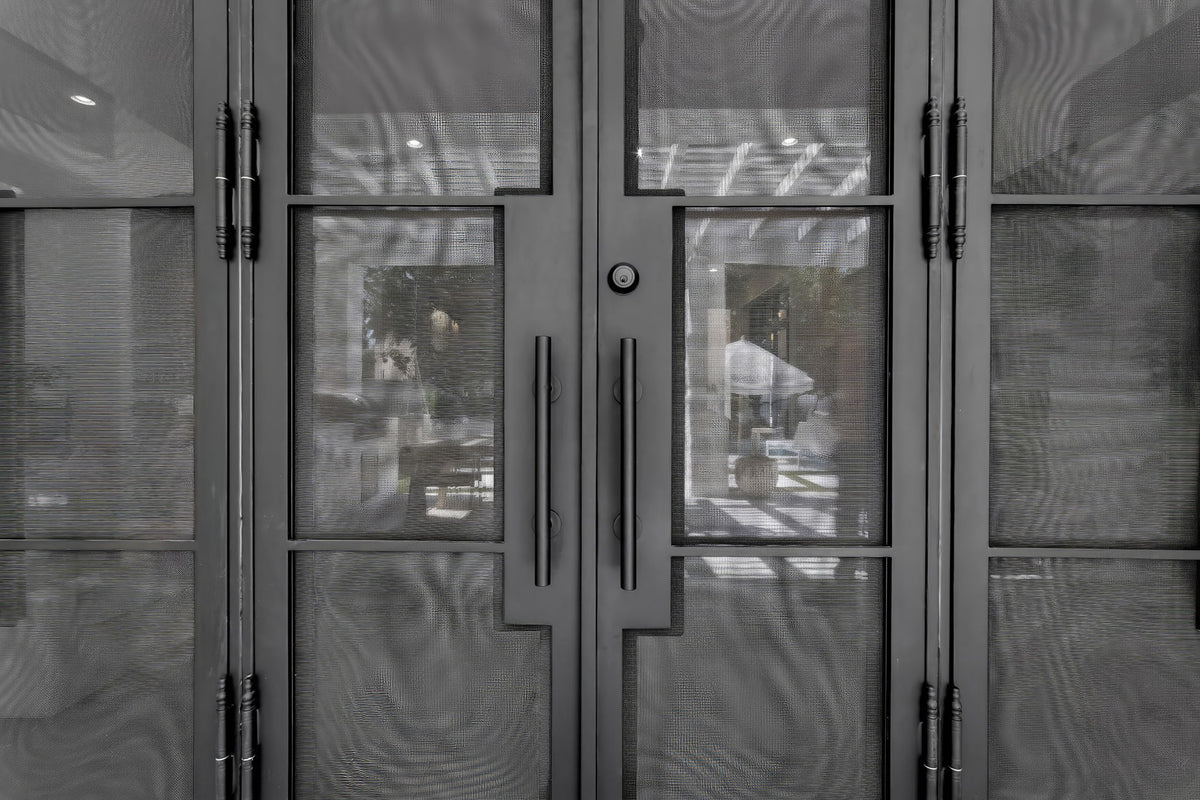 Close-up of black double doors with mesh panels, long vertical handles, decorative hinges, and a round lock.